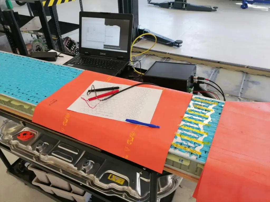 An opened pack on the bench with a hand-drawn cell map and measurement leads.