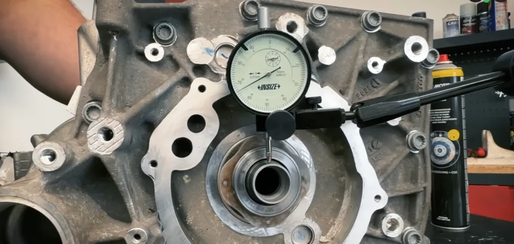 A dial indicator measuring runout in a drive unit bearing bore.